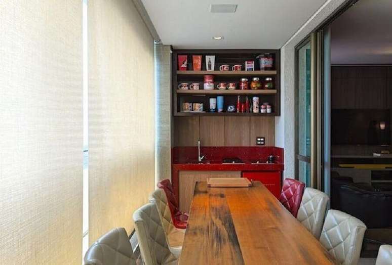 13. Apartamento com área gourmet pequena e simples planejada com bancada vermelha e mesa de madeira – Foto: Mariana Borges e Thaysa Godoy