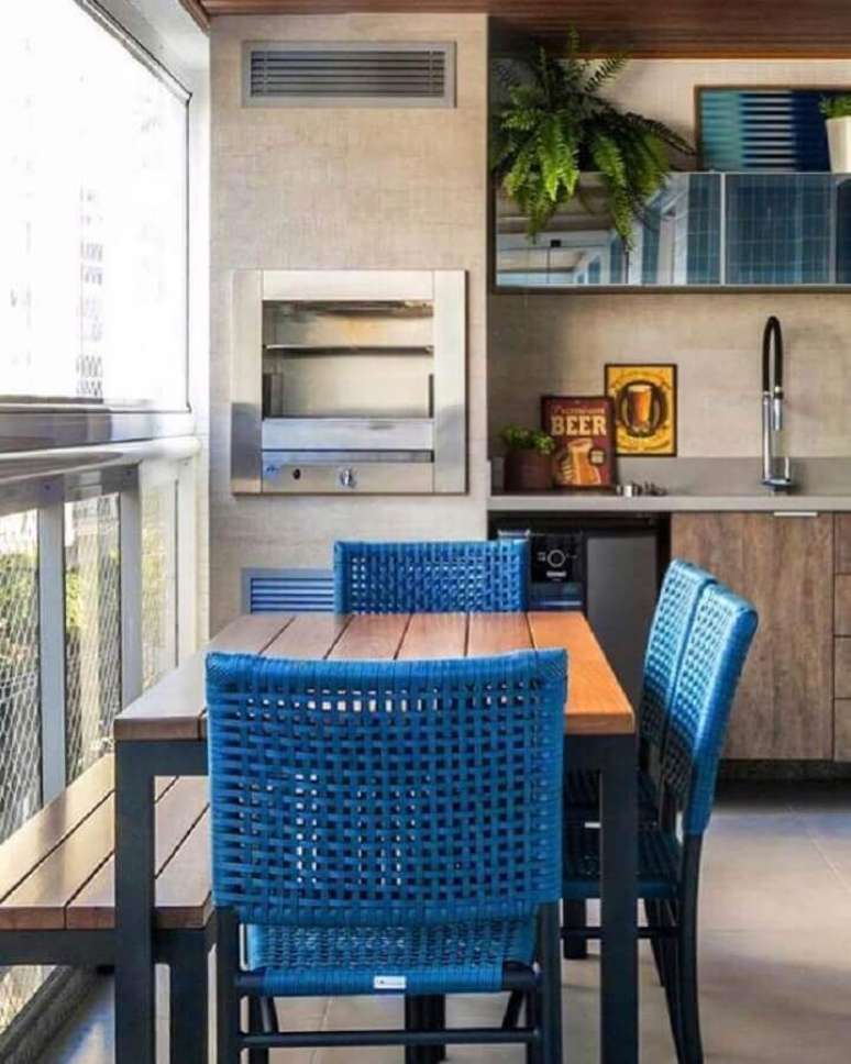 29. Cadeiras azuis e mesa de madeira para decoração de área gourmet pequena com churrasqueira – Foto: Pinterest