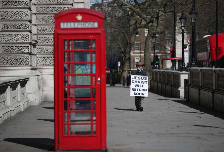 Homem segura cartaz em praça deserta em Londres
23/03/2020 REUTERS/Hannah McKay 