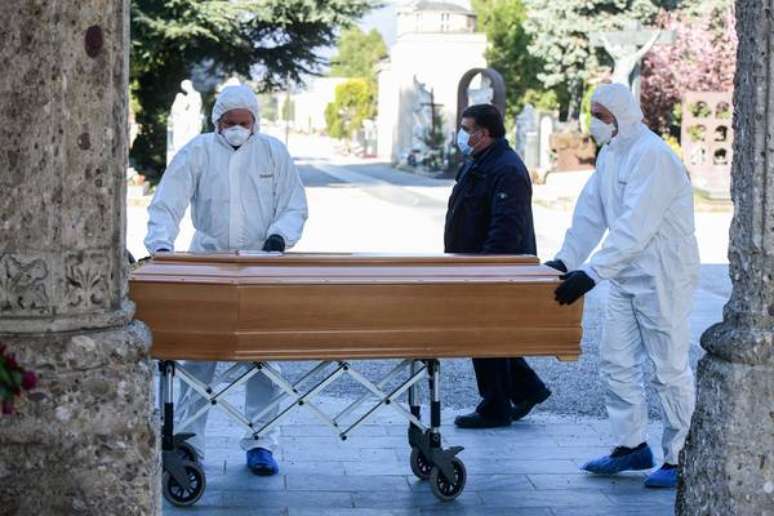 Operadores sanitários levam vítima de pandemia no Cemitério Monumental de Bergamo, norte da Itália