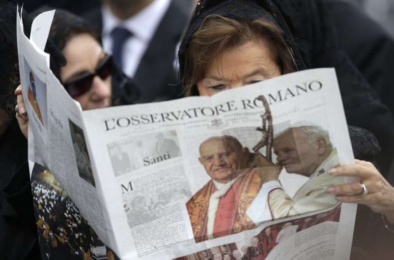 Mulher lê o periódico do Vaticano, "L'Osservatore Romano", na Praça de São Pedro 
27/04/2014
REUTERS/Max Rossi