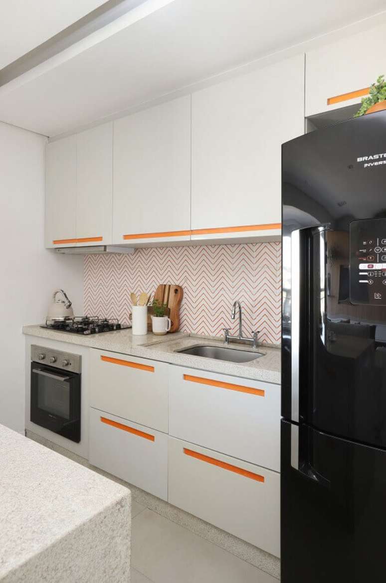 28. Decoração clean com armário de cozinha planejado com puxadores laranja e revestimento com desenhos geométricos – Foto: Studio Canto Arquitetura