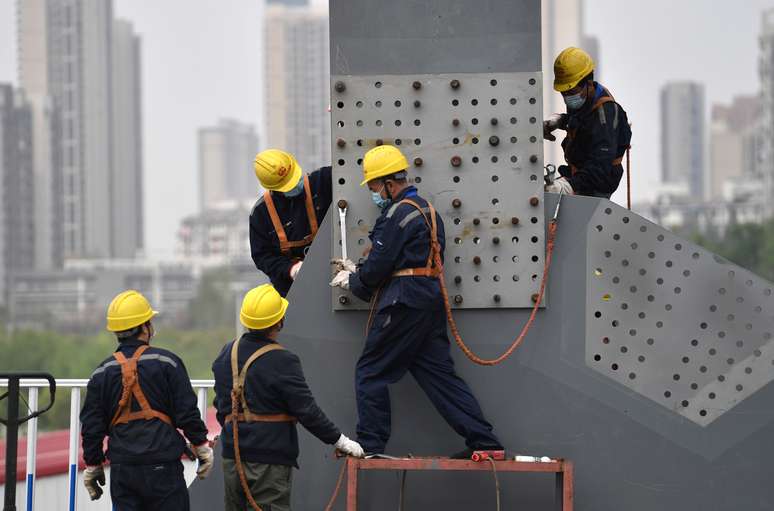 Trabalhadores com máscaras de proteção retomam obras em viaduto, em Wuhan
24/03/2020
China Daily via REUTERS 