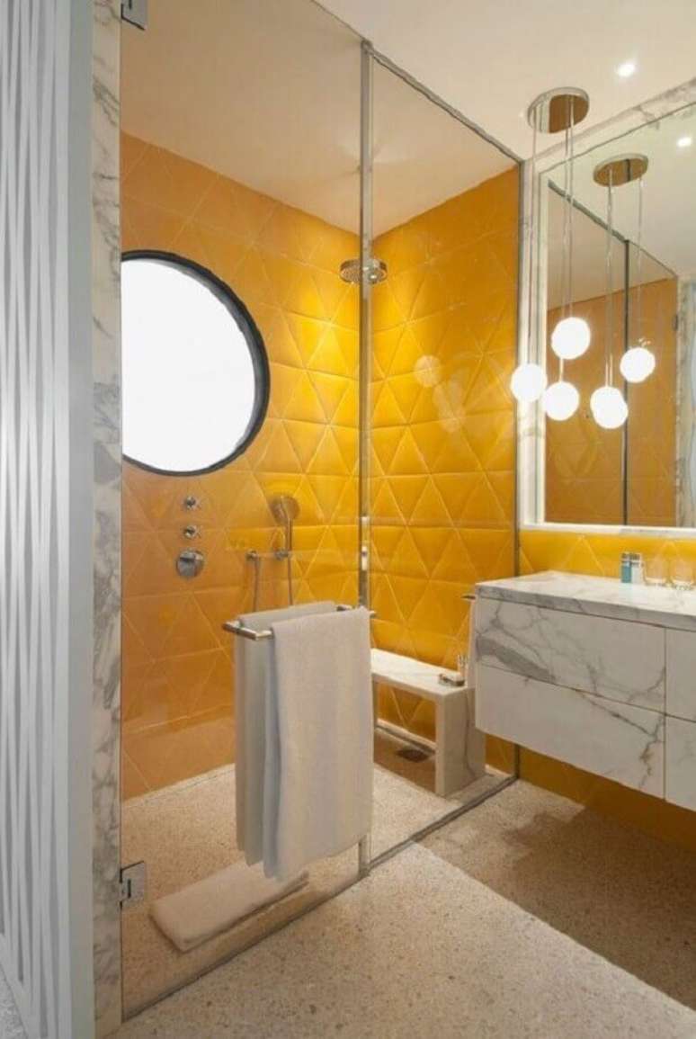 47. Lustre para banheiro moderno decorado com bancada de m&aacute;rmore e revestimento 3D amarelo para &aacute;rea do box &ndash; Foto: Casa Vogue