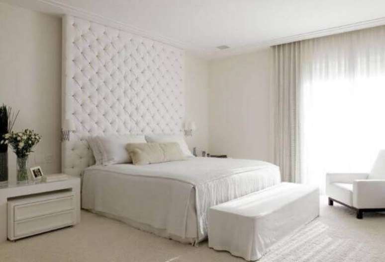 29. Quarto de casal com cabeceira alta de capiton&ecirc; e criado mudo branco. Projeto por Roberto Migotto