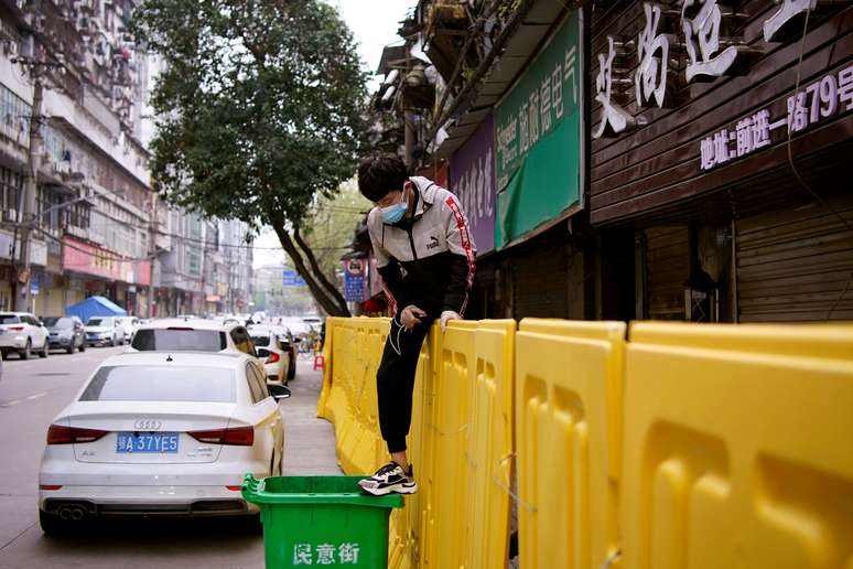 Jovem de máscara pula barreira de isolamento construída para separar prédios de rua em Wuhan
31/01/2020
REUTERS/Aly Song