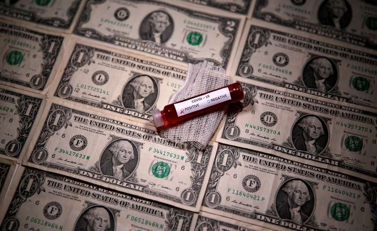 Tubo de ensaio contendo sangue falso marcado com a doença do coronavírus (Covid-19) é colocado sob notas de dólar norte-americano. 27/03/2020. REUTERS/Dado Ruvic/Ilustração.