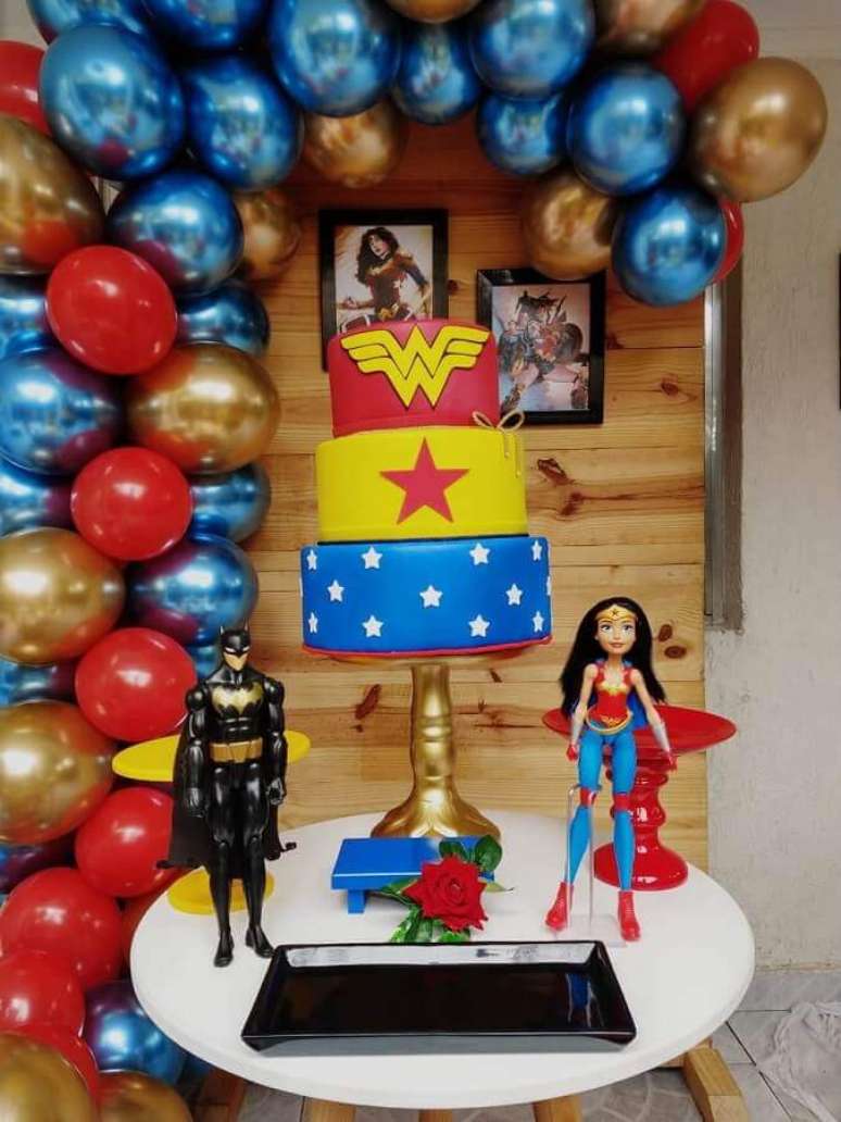 60. Painel de bal&otilde;es com acabamento metalizado para decora&ccedil;&atilde;o de festa Mulher Maravilha com boneco do Batman e Mulher Maravilha &ndash; Foto: Elo7