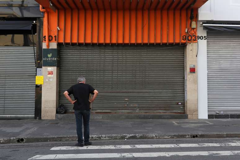 Homem em frente a uma loja fechada em São Paulo, em meio ao decreto que mandou fechar o comércio para evitar a disseminação do coronavírus. 20/3/2020. REUTERS/Amanda Perobelli 