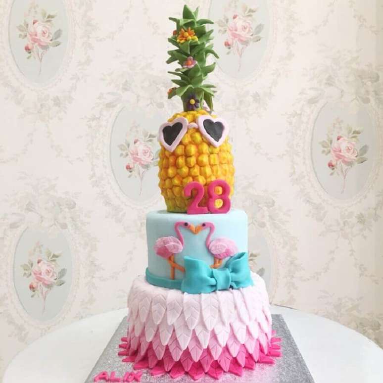 34. Divertido bolo tropical confeitado com flamingos e abacaxi no topo para festa de aniversário – Foto: Debogato