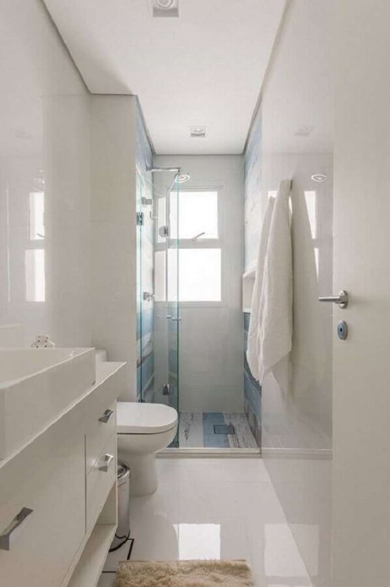 18. O banheiro branco ganha o detalhe do revestimento azul ao fundo no banheiro decorado – Foto: Idealizzare Arquitetura