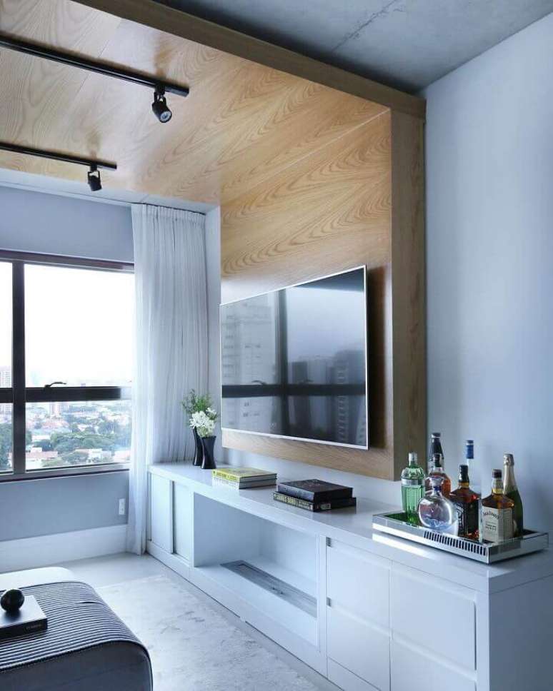 26. Decoração de apartamento pequeno com móveis planejados e painel de madeira que se estende pelo teto – Foto: Monise Rosa Arquitetura