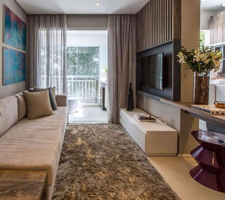 4. Apartamento decorado com sala de estar com tapete felpudo e painel de madeira para TV – Foto: Pinterest