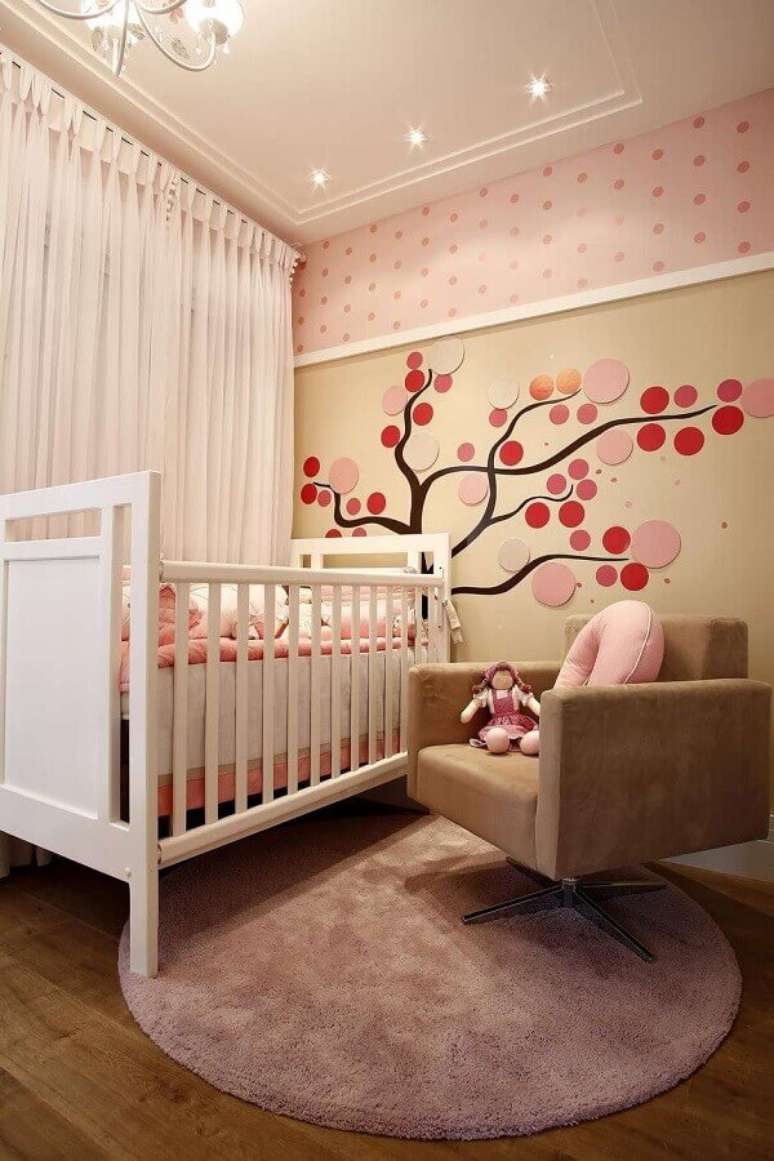 43. Poltrona bege para decoração de quarto de bebê rosa com papel de parede de bolinhas – Foto: Pinterest