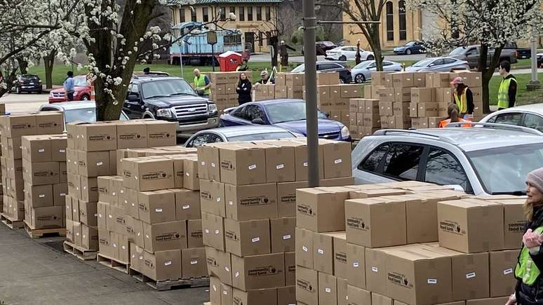 Muitos bancos de alimentos estão recorrendo à distribuição de comida em sistema de 'drive-thru', nos quais voluntários colocam uma caixa com mantimentos diretamente no porta-malas do carro