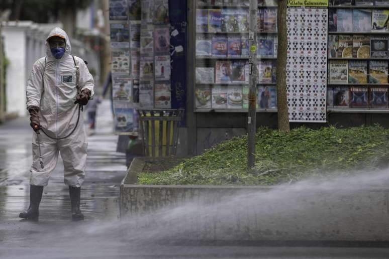 Funcionários realizam limpeza e desinfecção de calçada e mobiliário urbano em área da Avenida Paulista, região central de São Paulo