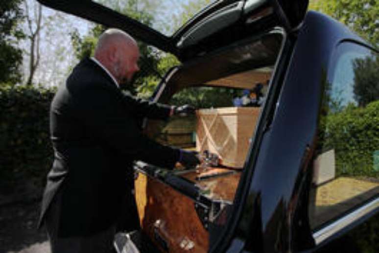 Funcionário de funerária coloca caixão na traseira de veículo na Inglaterra, em meio à pandemia do coronavírus. 22/4/2020. REUTERS/Molly Darlington