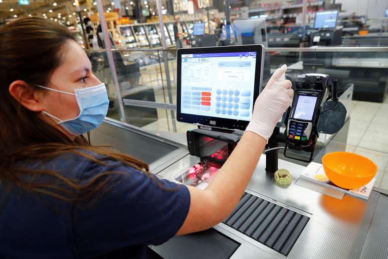 Uma mulher, que trabalha como caixa em um supermercado, limpa os instrumentos de trabalho em Bad Honnef, nas proximidades de Bonn, na Alemanha. 27/04/2020. REUTERS/ Wolfgang Rattay. 