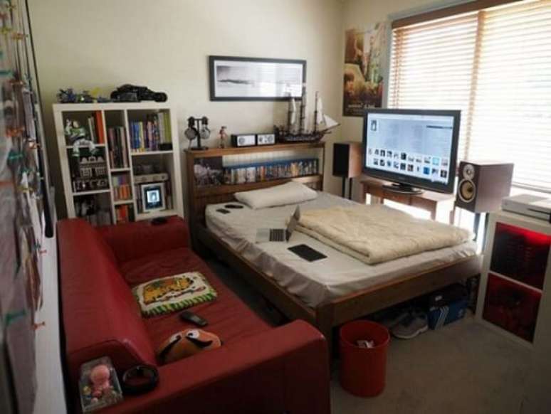 24. Quarto gamer pequeno com games acima da cama e TV em frente ao sofá