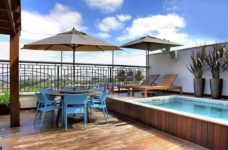 27. Deck de piscina pequena e espregui&ccedil;adeiras e mesa com ombrelone. Projeto de Studio Scatena