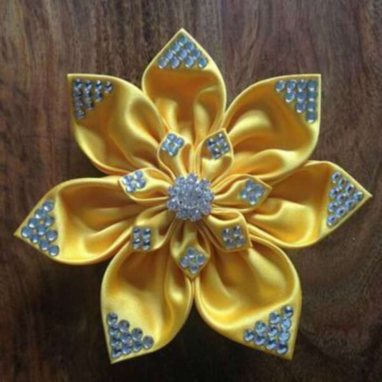51. A fita amarela mais pedraria deu uma flor de cetim linda &ndash; Foto: Via Pinterest