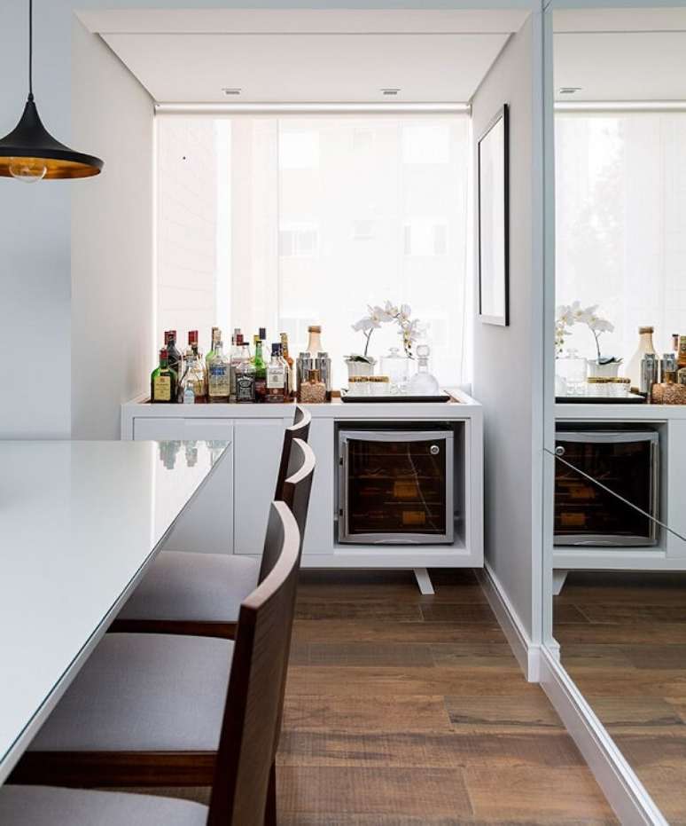 26. Organize seu home bar pequeno sobre um aparador em marcenaria branca. Projeto por Studio Novak