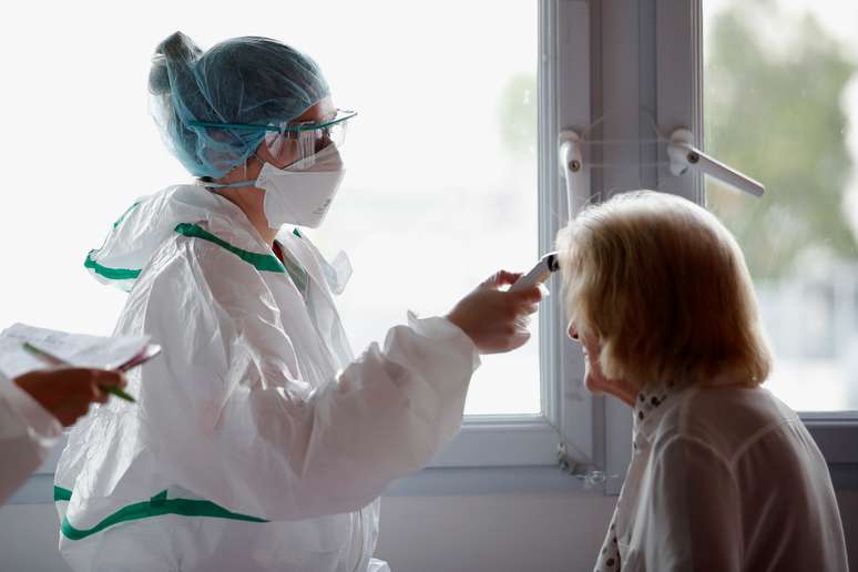 Uma enfermeira, com equipamento de proteção, checa a temperatura de uma paciente na França. 30/04/2020. REUTERS/Stephane Mahe. 
