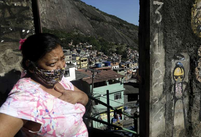 Uma mulher usa máscara protetora fica do lado de fora de sua casa, na favela da Rocinha, durante o surto de doença por coronavírus (COVID-19), no Rio de Janeiro