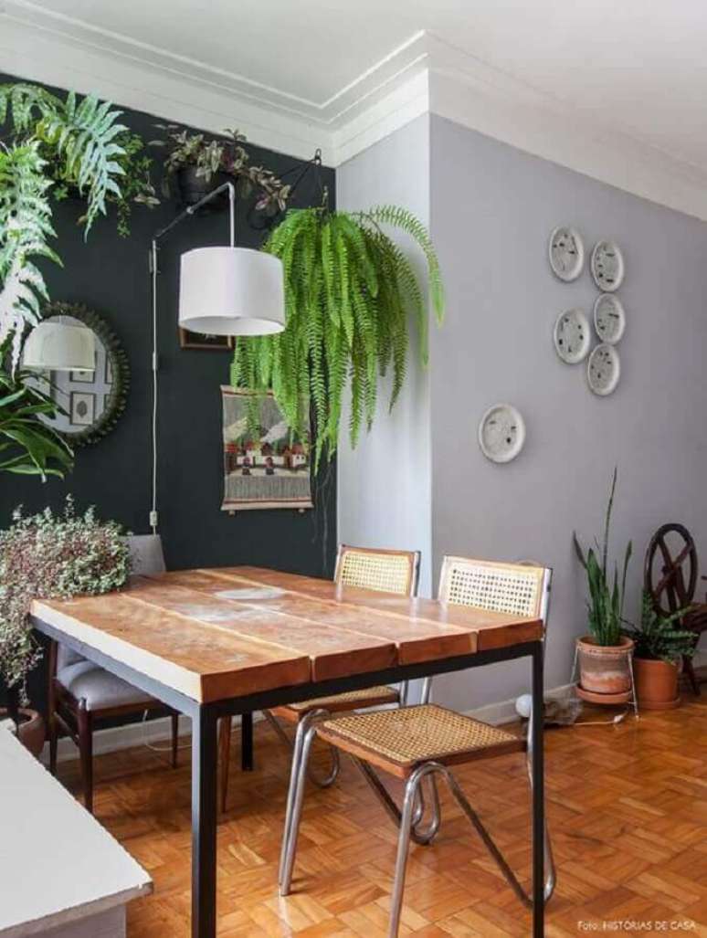 25. Sala de jantar decorada com parede pretas e várias espécies de plantas pendentes – Foto: Casa de Valentina