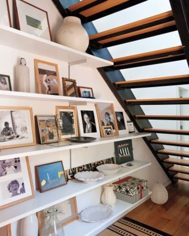 7. Decoração embaixo da escada vazada com prateleiras e porta retratos – Via: Satori Design for Living