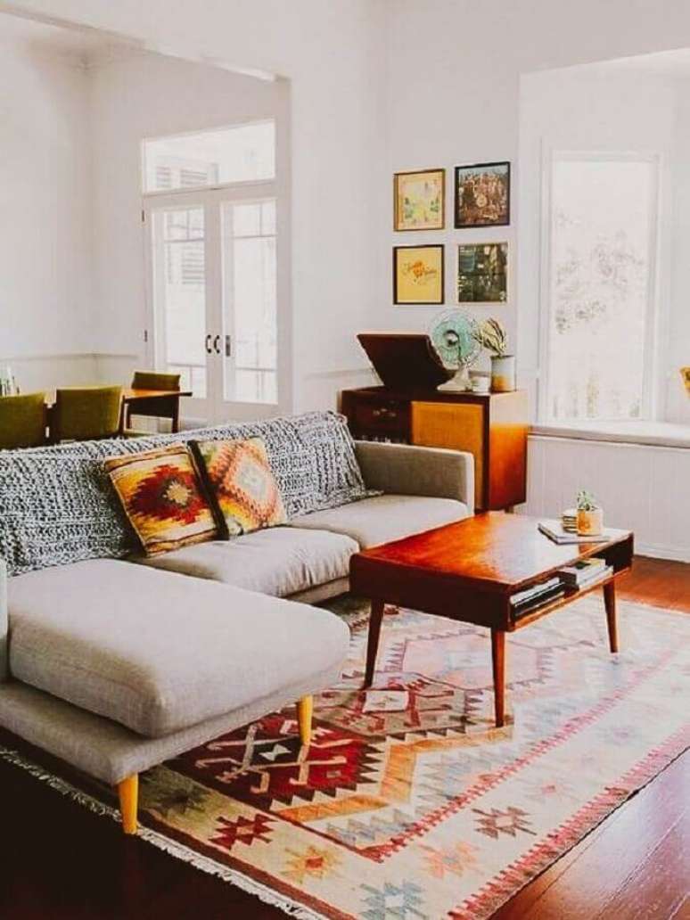 92. Tapete pra sala de jantar simples decorada com sofá com chaise e mesa de centro de madeira – Foto: A Casa Delas