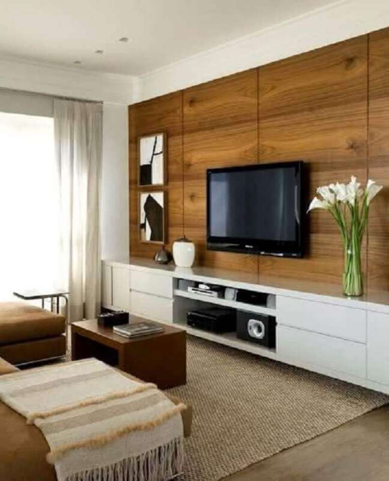 103. Sala de estar decorada com tapete sisal e painel de madeira para TV – Foto: Decostudio