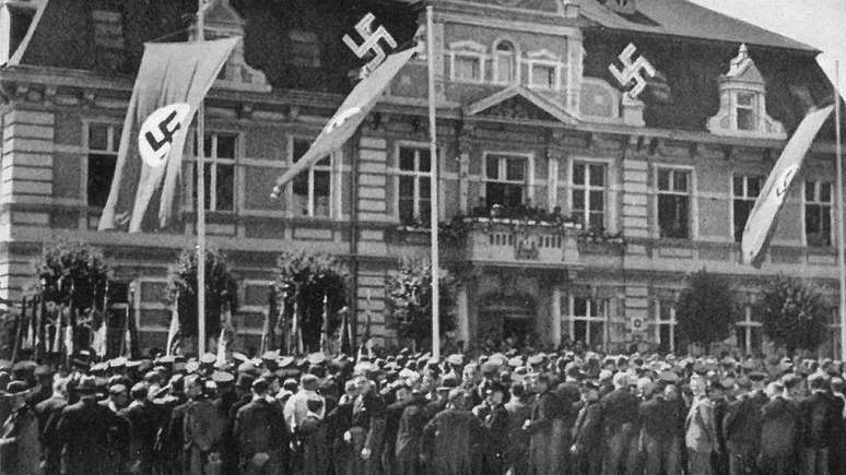 Multidão diante de edifício público em Demmin, decorado com bandeiras nazistas em 1936; cidade tinha histórico de apoio ao partido de Hitler