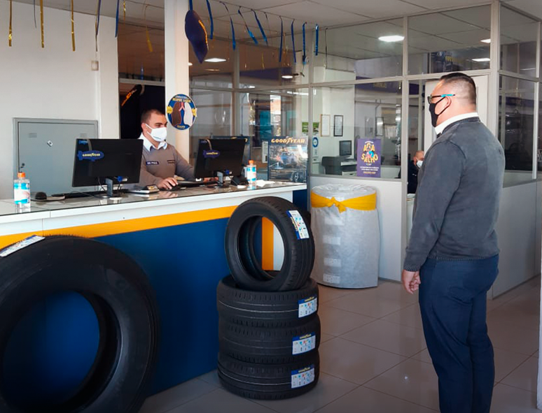 Uma pilha de pneus é colocada à frente do atendente para evitar o contato com os clientes.