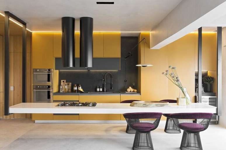 12. Decoração moderna para cozinha completa com armário planejados amarelos e ilha grande com cooktop – Foto: Diego Revollo