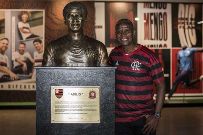 Adílio posa ao lado de seu busto, inaugurado em julho de 2019, na Gávea (Foto: Paula Reis/Flamengo)