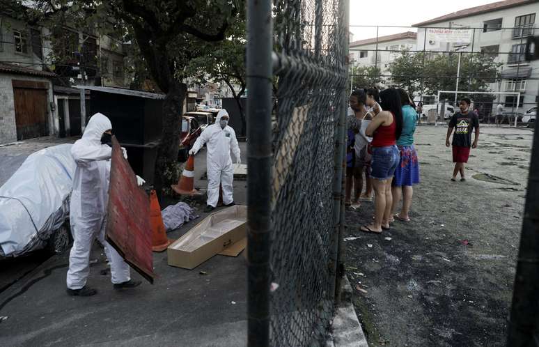 Funcionários do serviço funerário, usando roupas de proteção, recolhem o corpo de uma pessoa que morreu por problemas respiratórios em meio à pandemia do coronavírus, no Rio de Janeiro. 17/5/2020. REUTERS/Ricardo Moraes