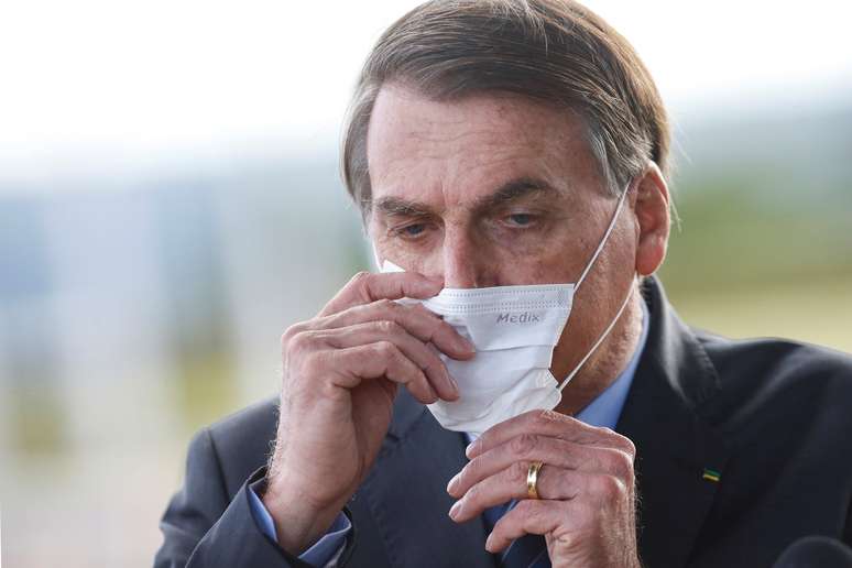 Bolsonaro ajusta máscara ao deixar Palácio da Alvorada 13/5/ 2020 REUTERS/Adriano Machado