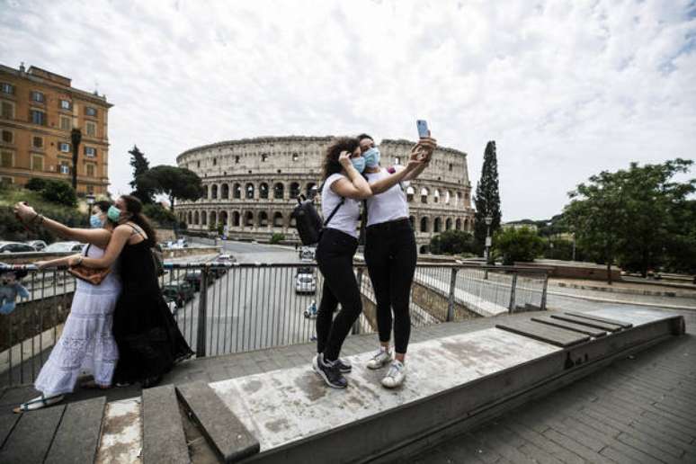 Amigas tiram fotos em frente ao Coliseu de Roma, na Itália: o turismo entre regiões ainda está proibido