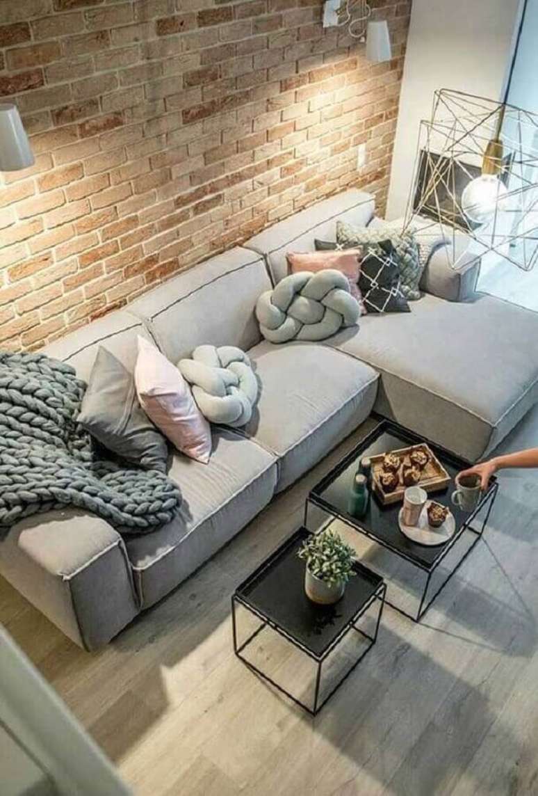 27. Almofadas para sofá com chaise cinza em sala decorada com parede de tijolo à vista – Foto: Futurist Architecture