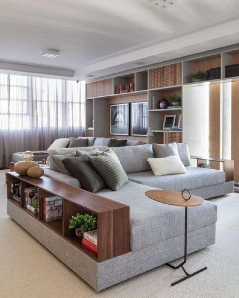 46. Modelo de sofá moderno em L com aparador de madeira na lateral – Foto: Arquitrecos
