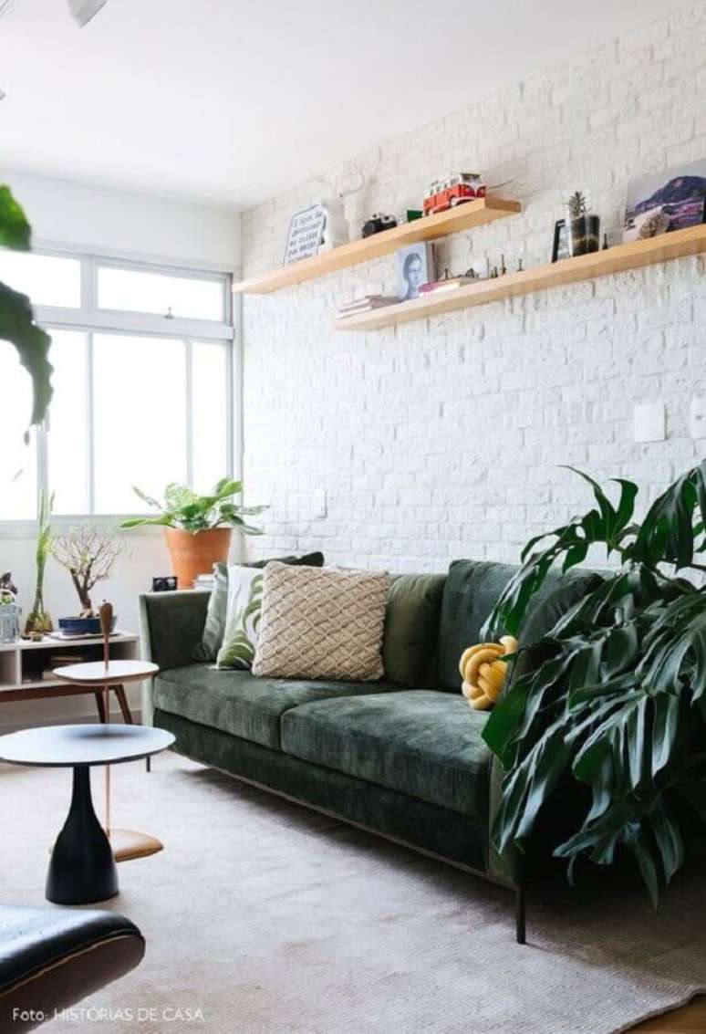 19. Sala branca decorada com sof&aacute; de veludo verde e prateleiras de madeira &ndash; Foto: Constance Zahn