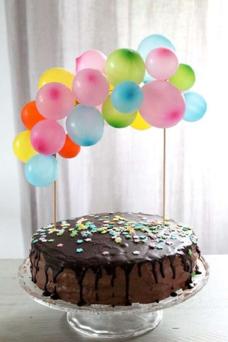 18. Bolo de chocolate decorado com vários pequenos balões coloridos para festa de aniversário infantil simples – Foto: Brit+Co