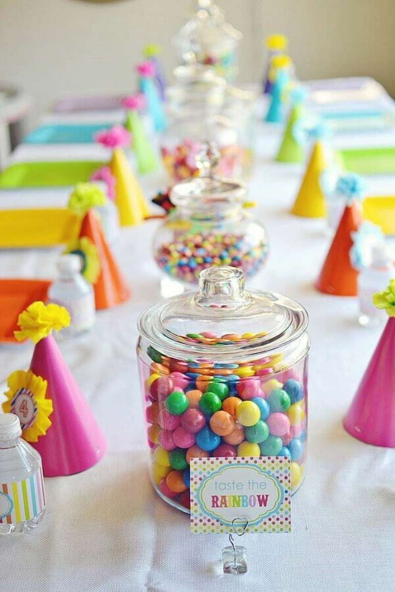 28. Decoração festa infantil simples bonita com balinhas coloridas em potes de vidros e pratos e chapeuzinhos coloridos – Foto: PopSugar