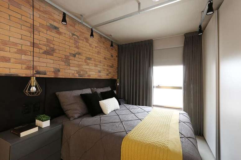 41. Decora&ccedil;&atilde;o com parede de tijolo &agrave; vista e cabeceira casal preta com criado mudo &ndash; Foto: SP Est&uacute;dio