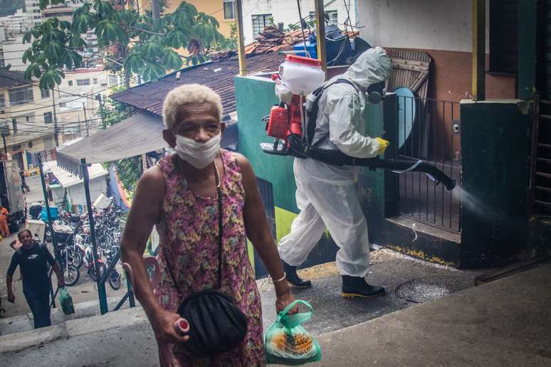 Moradores da comunidade do Santa Marta, zona sul do Rio de Janeiro, usando roupas de proteção, fazem higienização por conta própria na favela