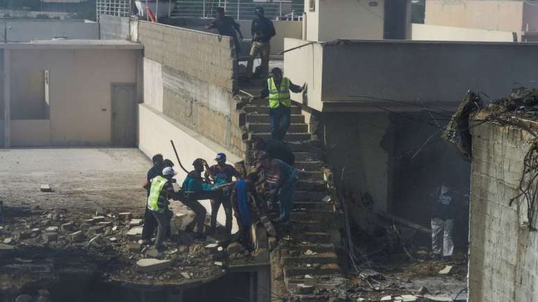 Residentes ajudam a retirar uma pessoa dos escombros; diversas casas foram destruídas