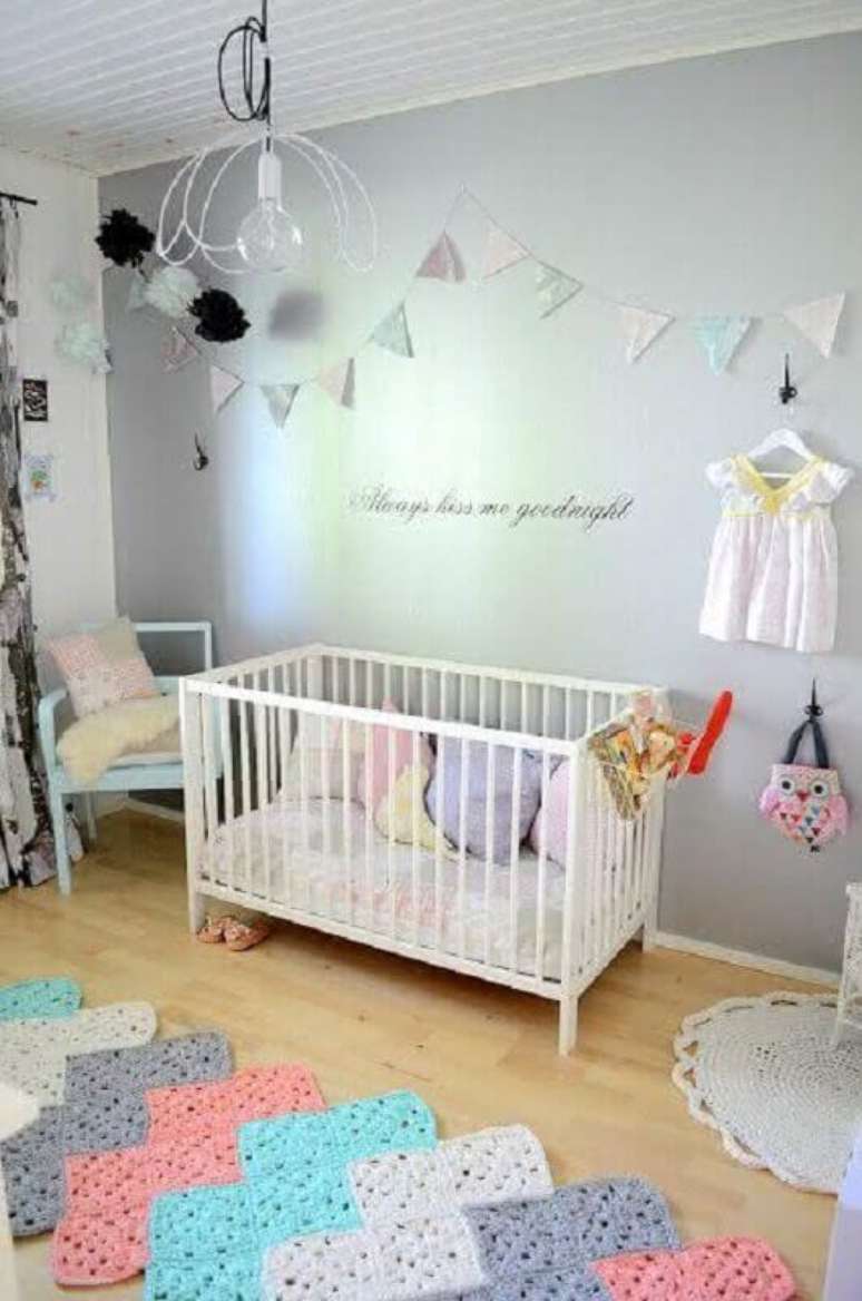 17. Modelo colorido de tapete de crochê para quarto de bebê com berço branco e bandeirinhas coloridas na parede – Foto: Archilovers