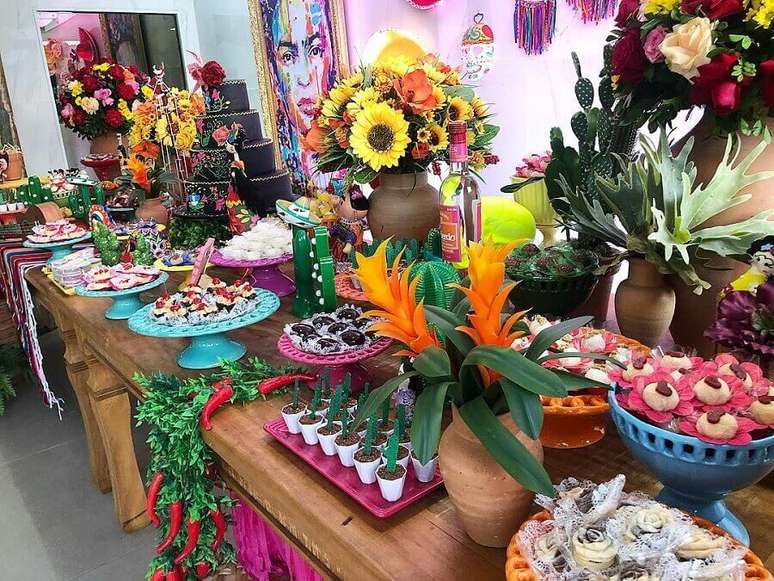 30. Decoração festa mexicana com grandes arranjos de flores e vários pratos coloridos para doces – Foto: Bello Toque