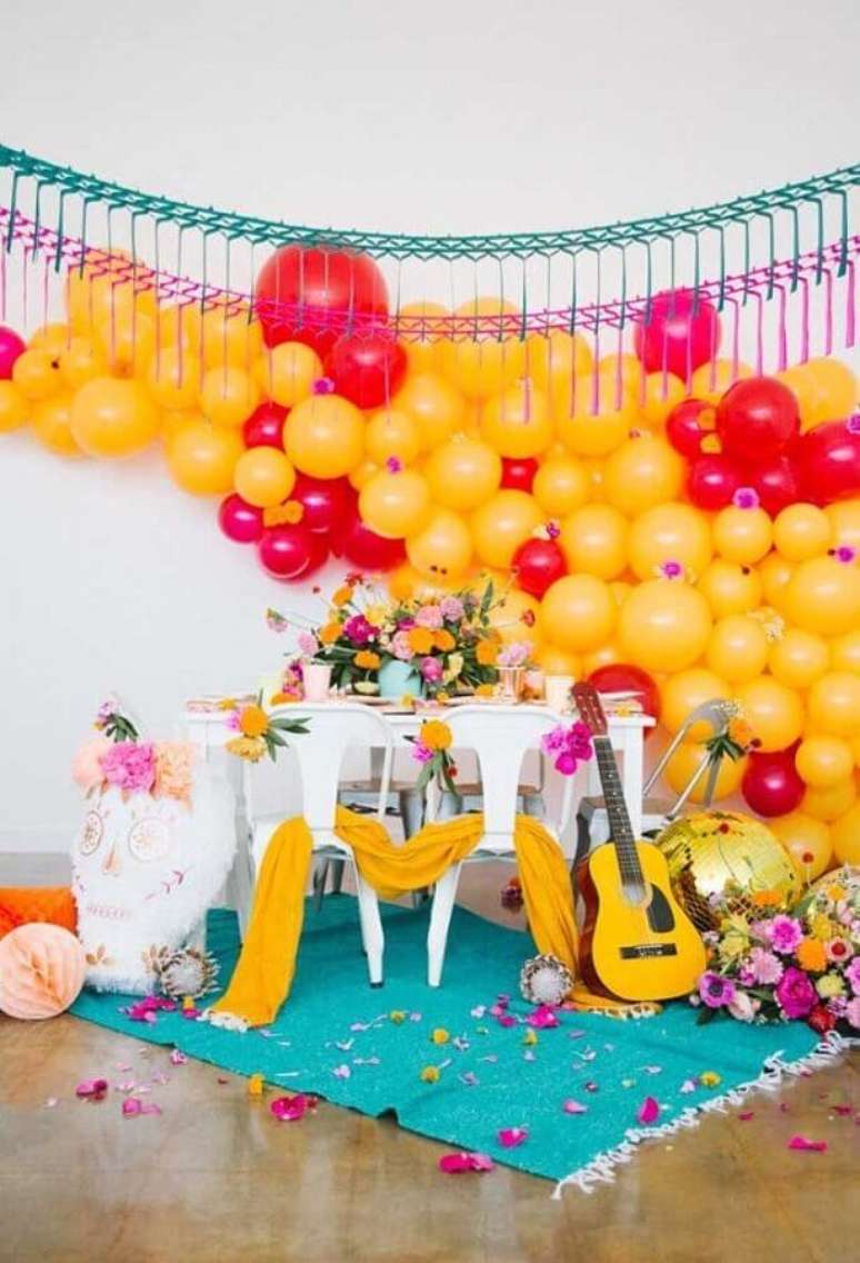 32. Decoração festa mexicana com painel de balões amarelos e vermelhos e arranjos de flores – Foto: 100 Layer Cakelet